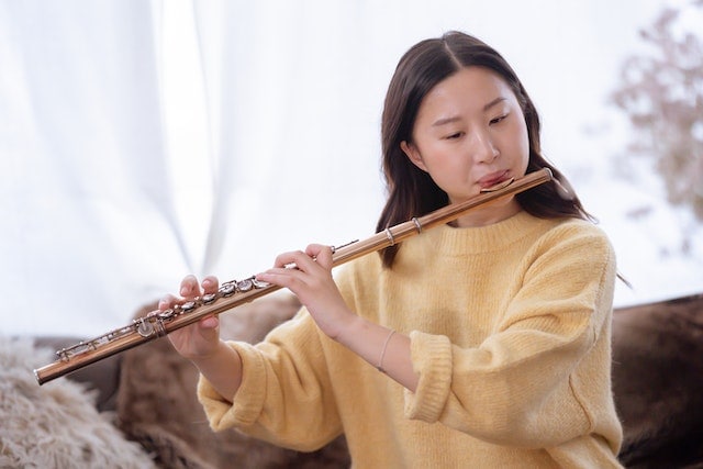 Asian woman playing flute at home