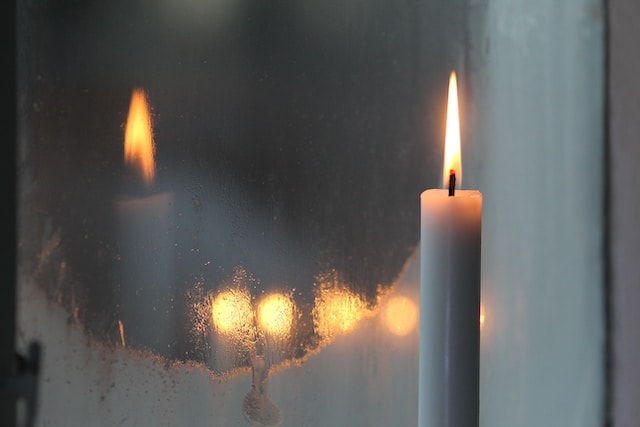 a lit candle in front of a mirror
