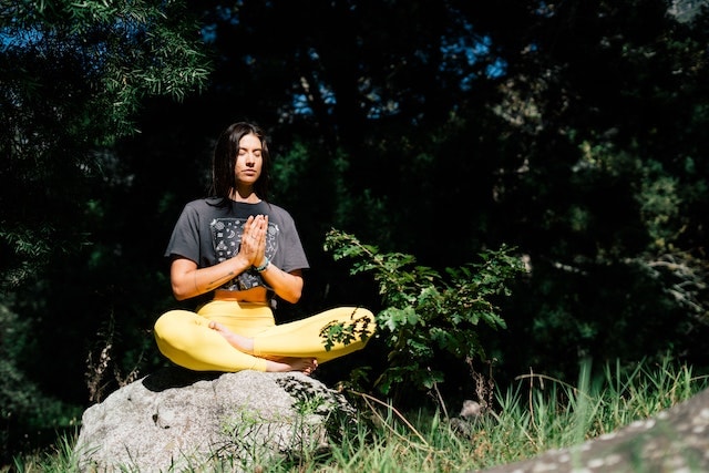 a woman meditating on top of a rock