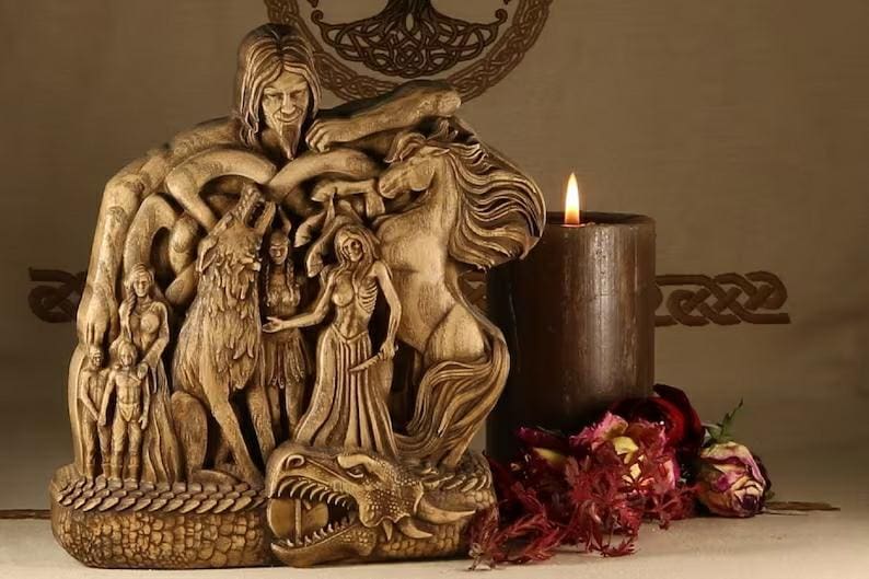 norse gods statue beside a candle and flowers