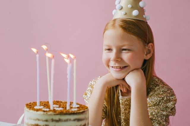 Girl Smiling in Front of a Cake